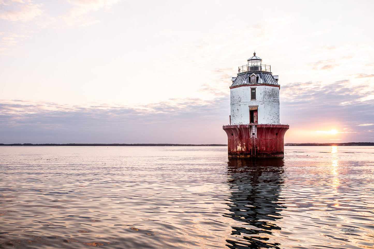 Crimson Sentry — A red and white sparkplug-style lighthouse standing alone in the Chesapeake Bay under a soft, clouded sunset sky with gentle ripples in the water.
